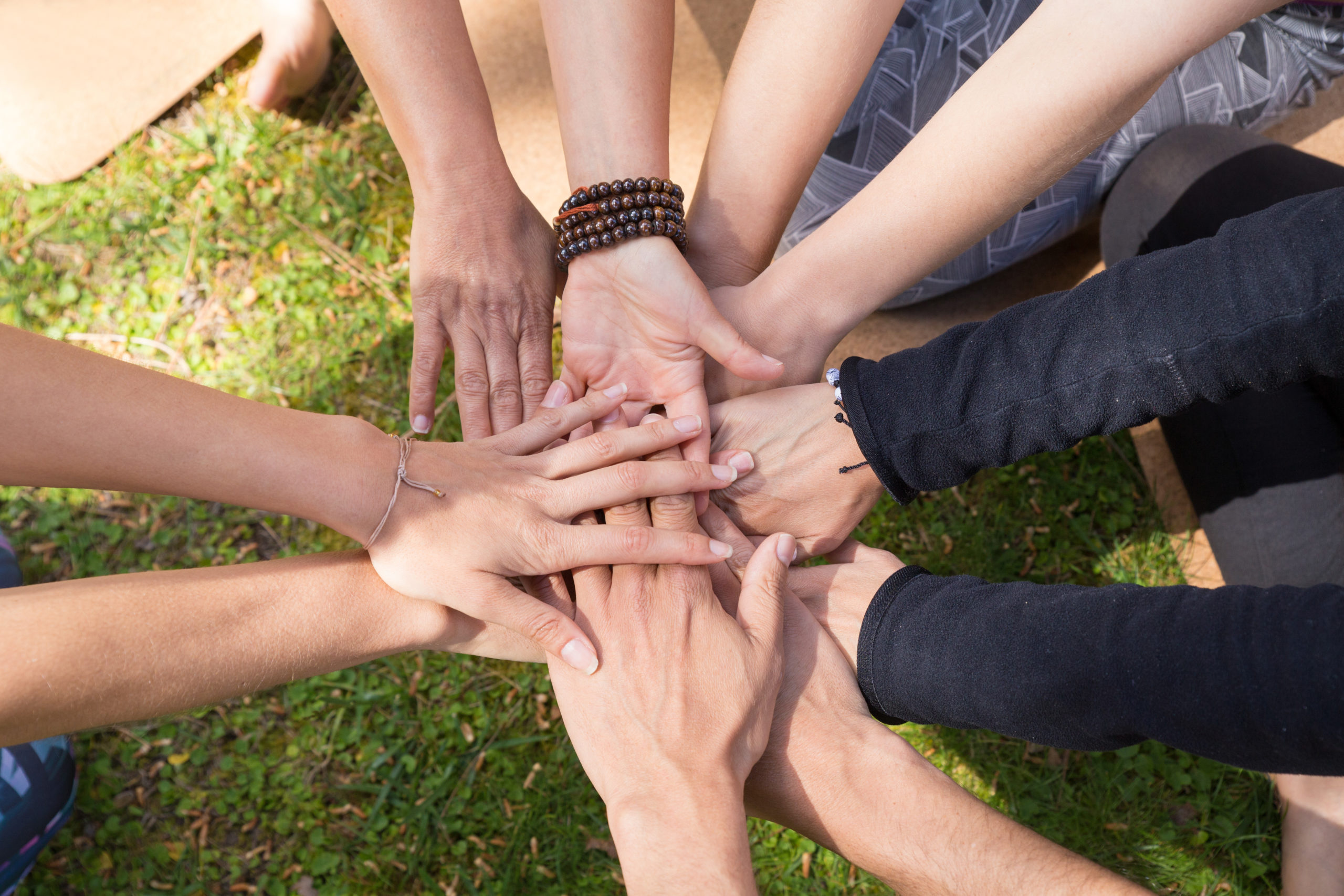 Top view of stack of hands against green grass